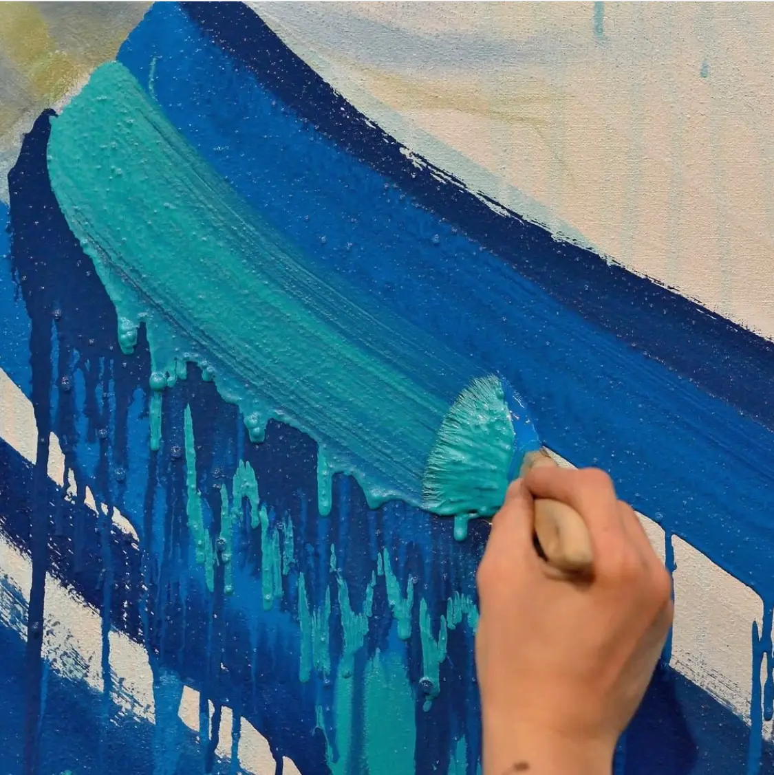 Mano che dipinge con pennello delle pennellate blu e azzurre